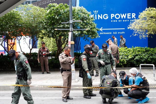 Thai forensic police officers inspect the area where one of a number of small bombs exploded in Bangkok on Friday