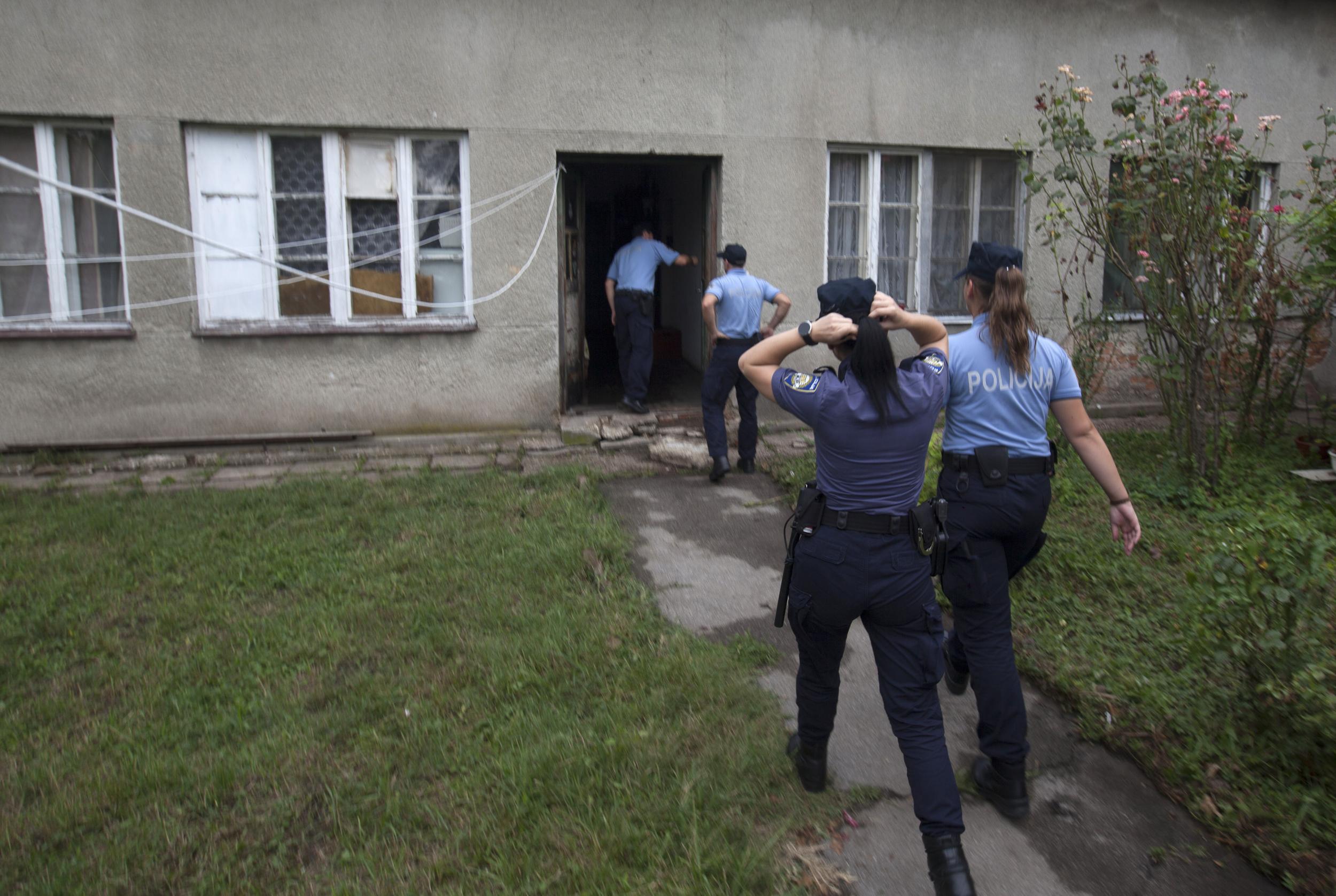 Police enter the house where a suspect killed six people, including a ten-year-old child, before committing suicide