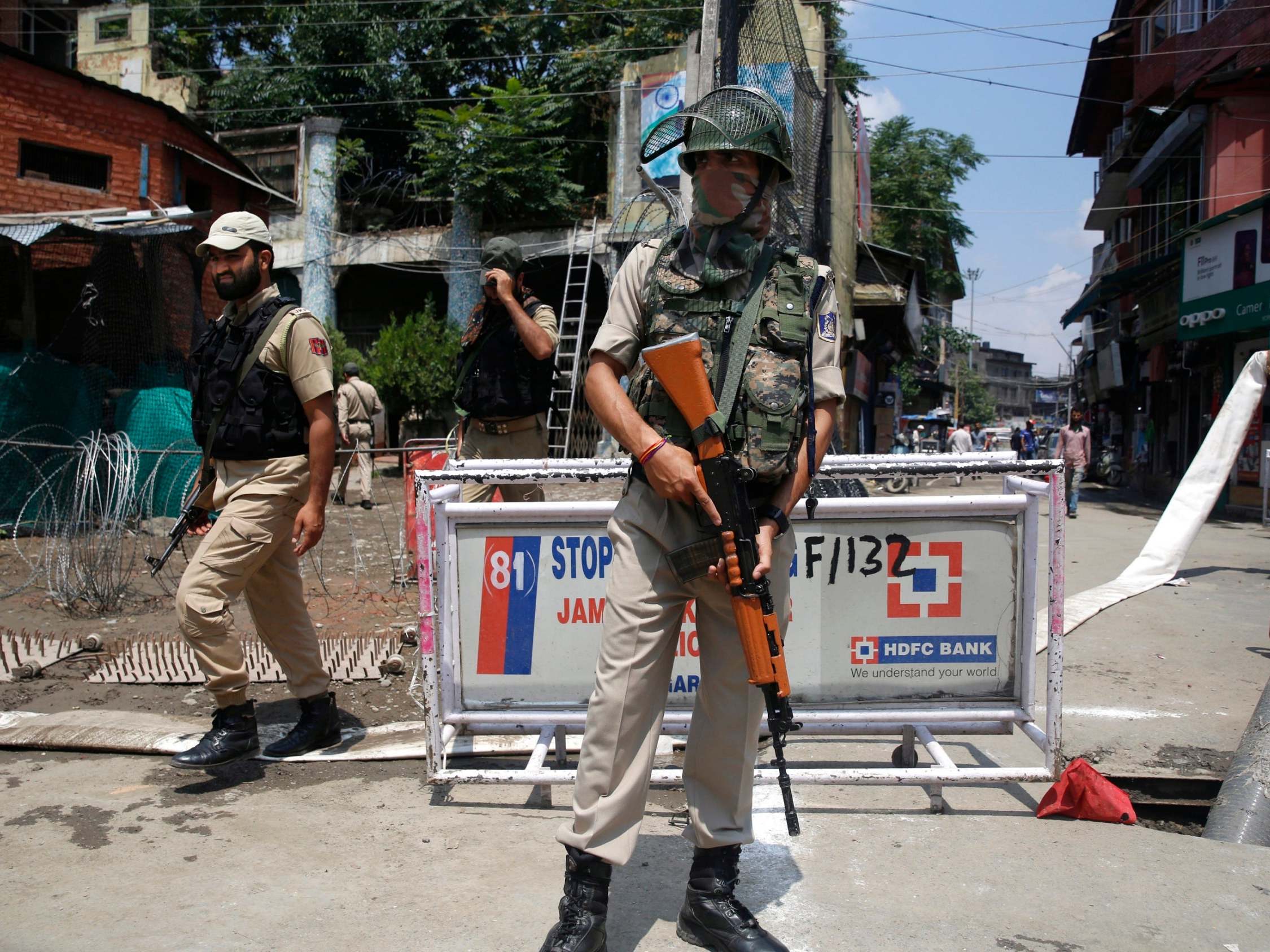 An Indian paramilitary soldier stands guard as policemen walk past in Srinagar on Friday