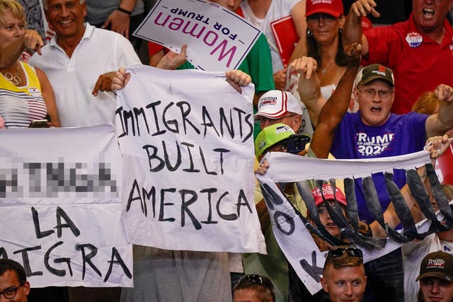 Protesters hold banners reading "immigrants built America" at a Trump rally in Cincinatti, Ohio