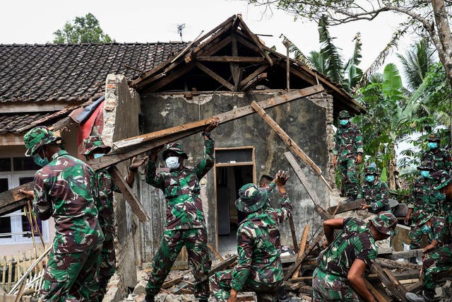 Indonesian military personnel inspect a damaged house after a 6.9 magnitude earthquake
