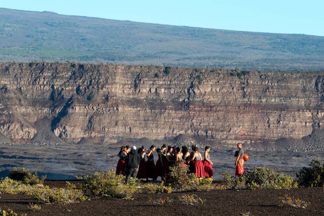A group of Native Hawaiians stand next to the collapsed crater floor of the volcano