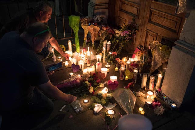 Two men light candles at a makeshift memorial as they take part of a candle lit vigil in honor of those who lost their lives or were wounded in a shooting in Dayton, Ohio on August 4, 2019
