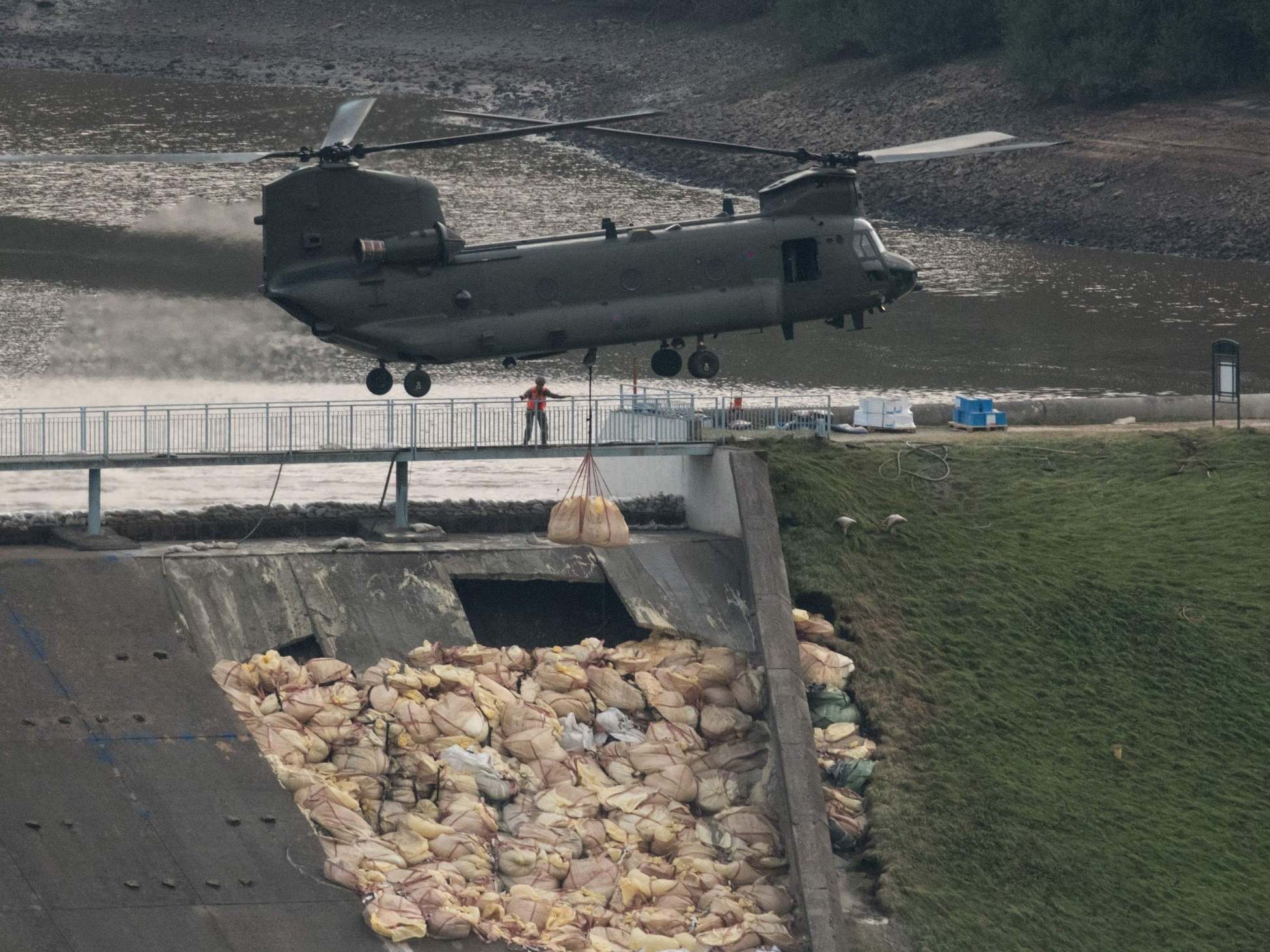 An RAF Chinook helicopter drops more bags of aggregate on the damaged section of spillway of the Toddbrook Reservoir dam