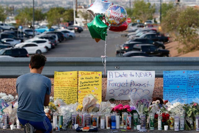 A young man prays while attending the make shift memorial along the street after the mass shooting that happened at a Walmart in El Paso