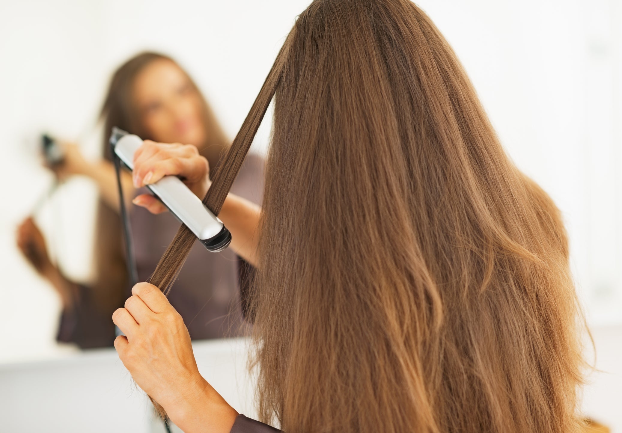 Woman straightening hair with straightener