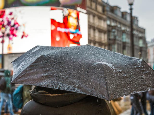 Rain on a pedestrian's umbrella during a heavy shower in Piccadilly Circus