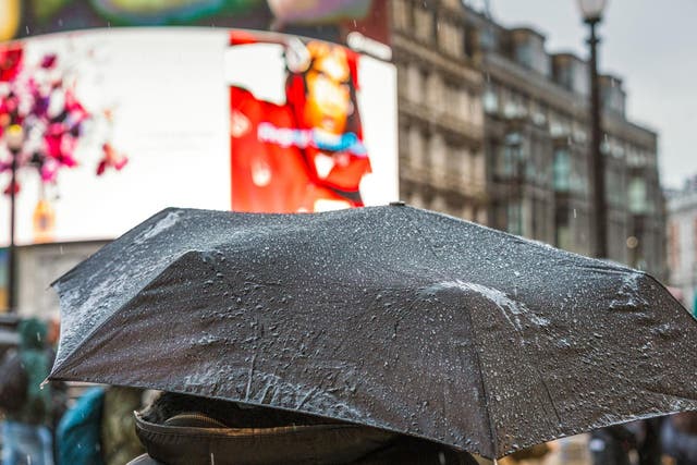 Rain on a pedestrian's umbrella during a heavy shower in Piccadilly Circus