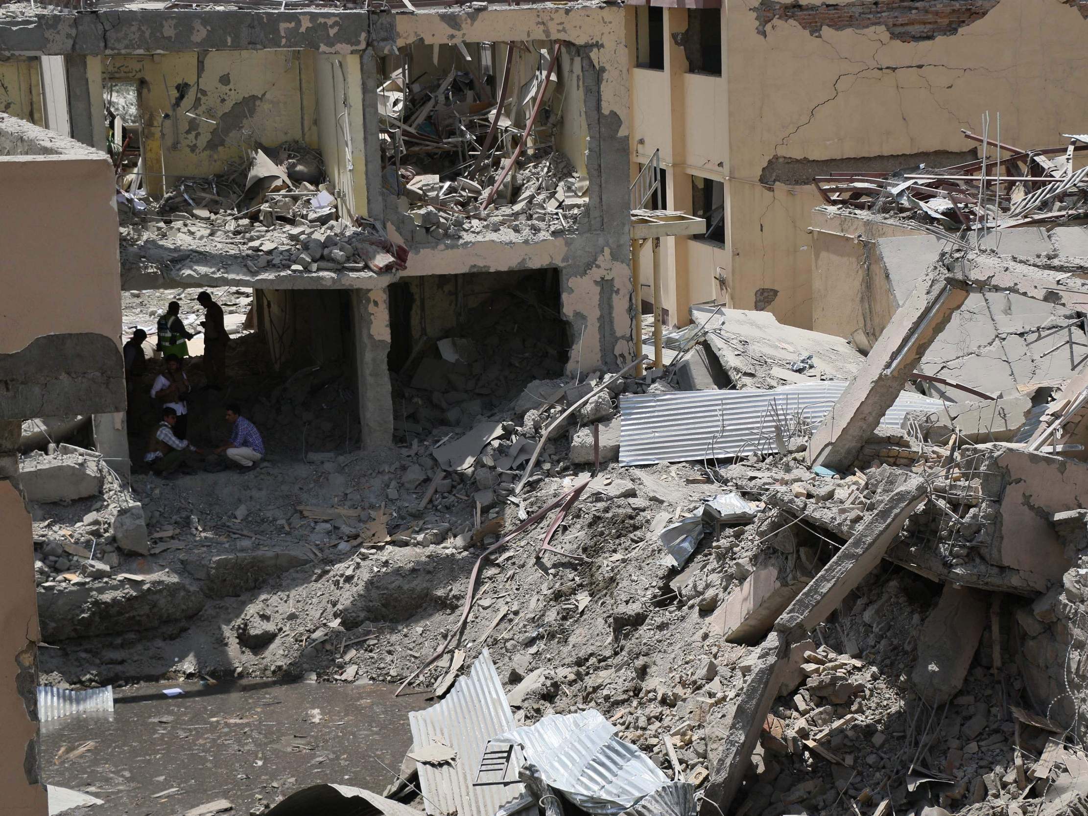Afghan security forces investigate the site where a Taliban car bomb detonated at the entrance of a police station in Kabul