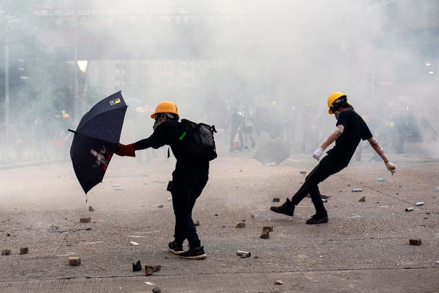 <p>Anti-extradition protesters react after teargas is fired by police during clashes in Wong Tai Sin on 5 August</p>