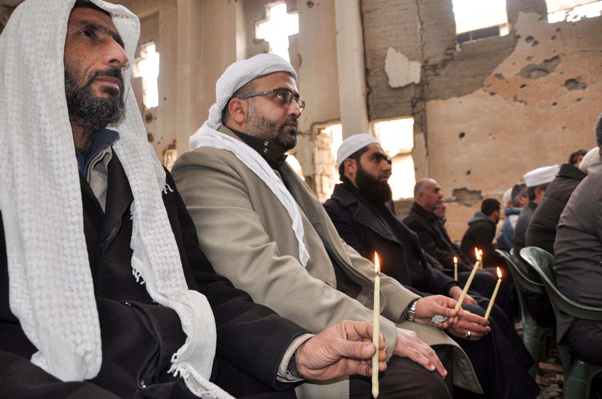 Muslim clerics at a mass held by the Syriac Orthodox Patriarch of Antioch, Ignatius Aphrem II, at the heavily damaged church of St Mary in Syria’s eastern city of Deir Ezzor (AFP/Getty)