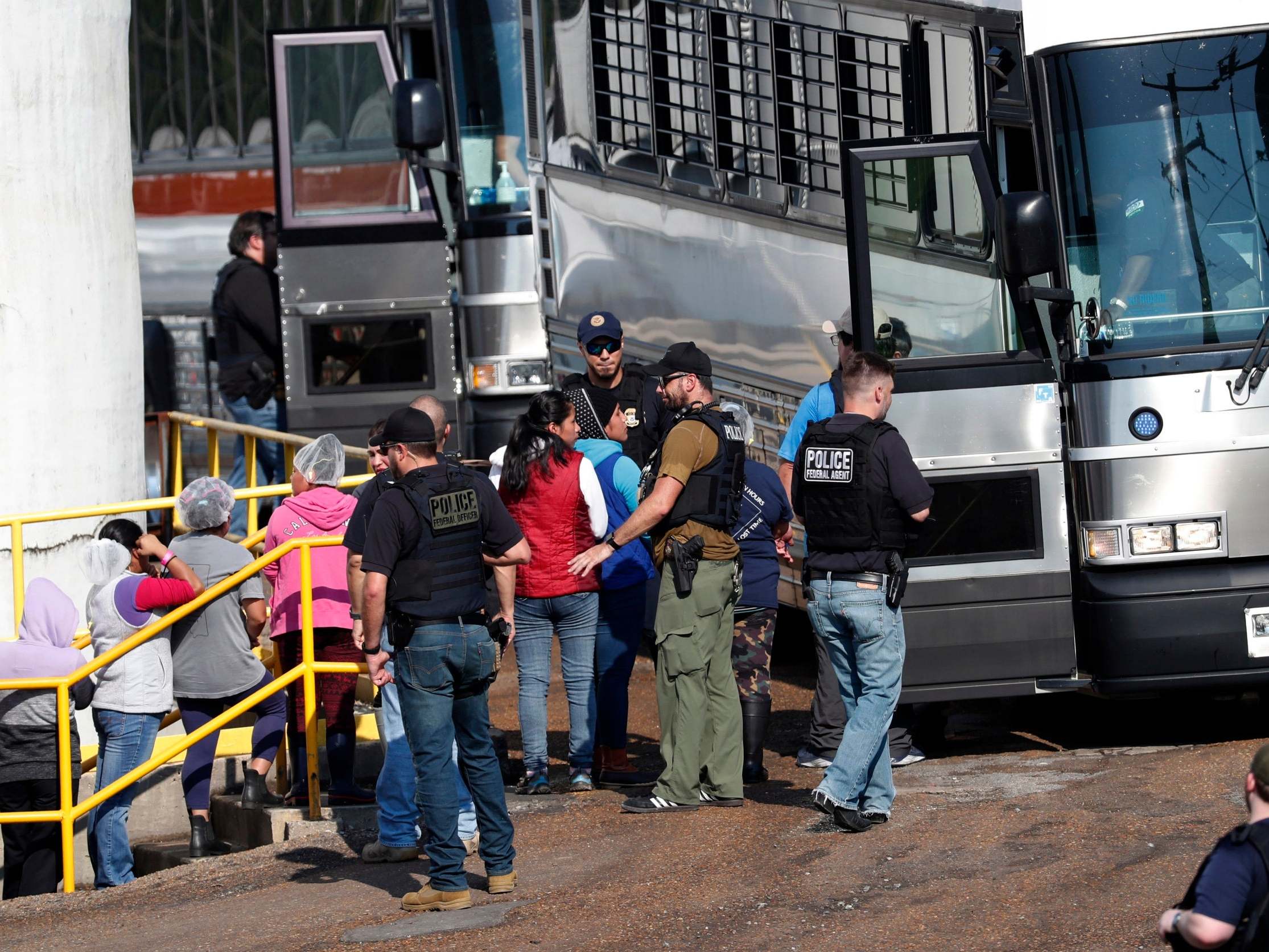 Handcuffed female workers are escorted onto a bus following a raid by US immigration officials at a Koch Foods Inc. plant in Morton, Mississippi, 7 August 2019.
