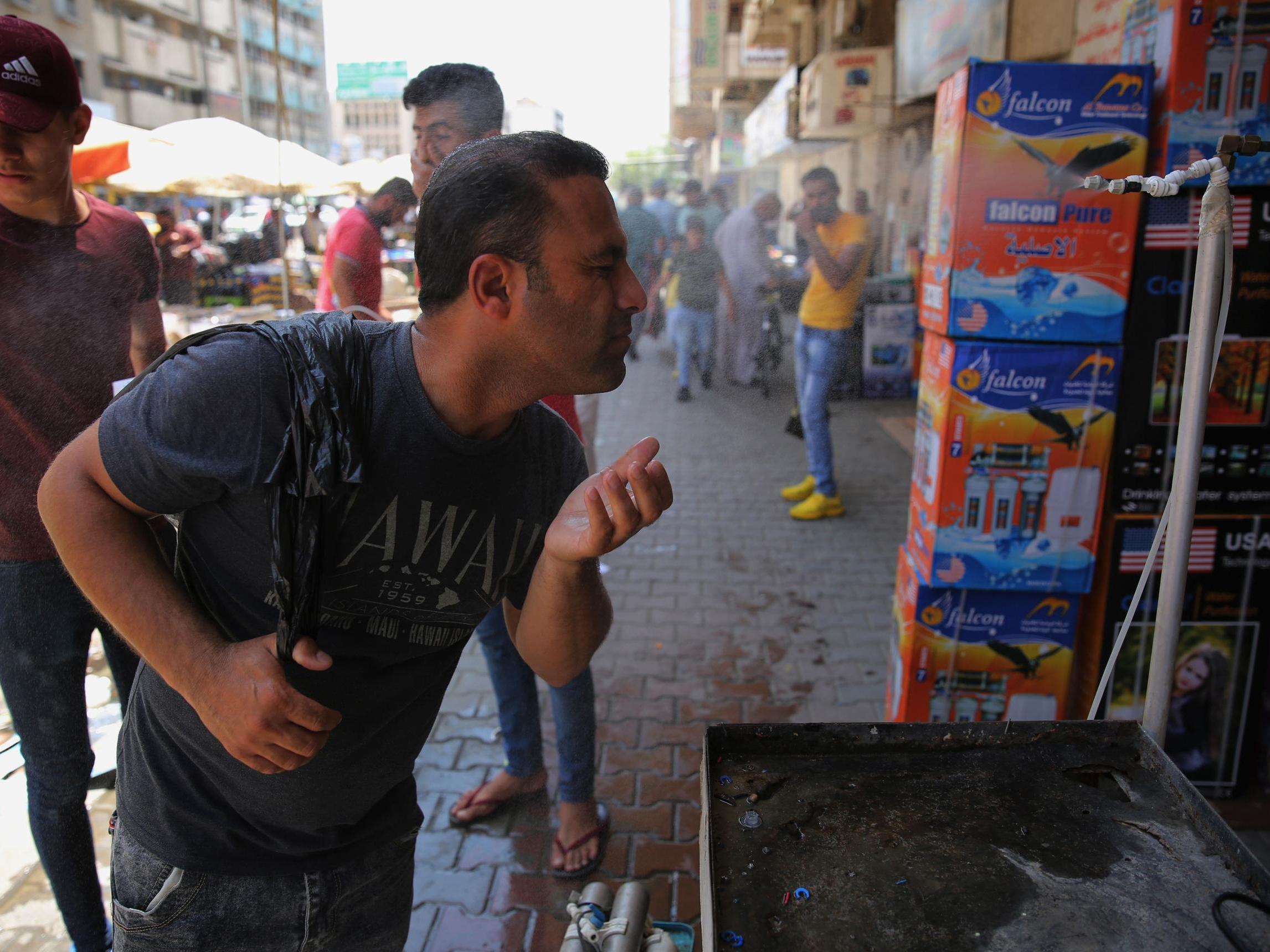 An Iraqi man uses a curbside shower to cool off during a heat wave in the capital Baghdad in June