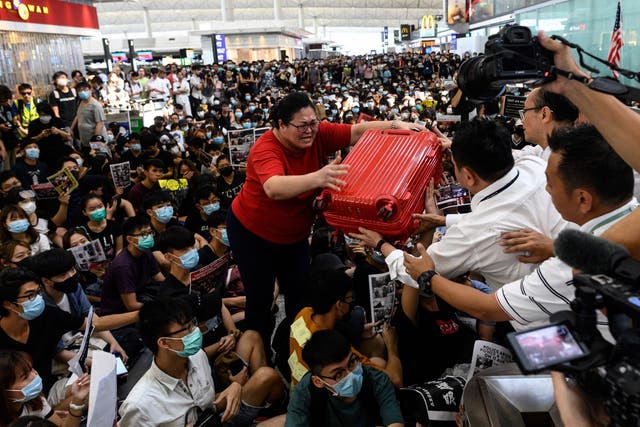 A tourist gives her luggage to security as she tries to enter the gate during a pro-democracy protest at Hong Kong international airport on Tuesday