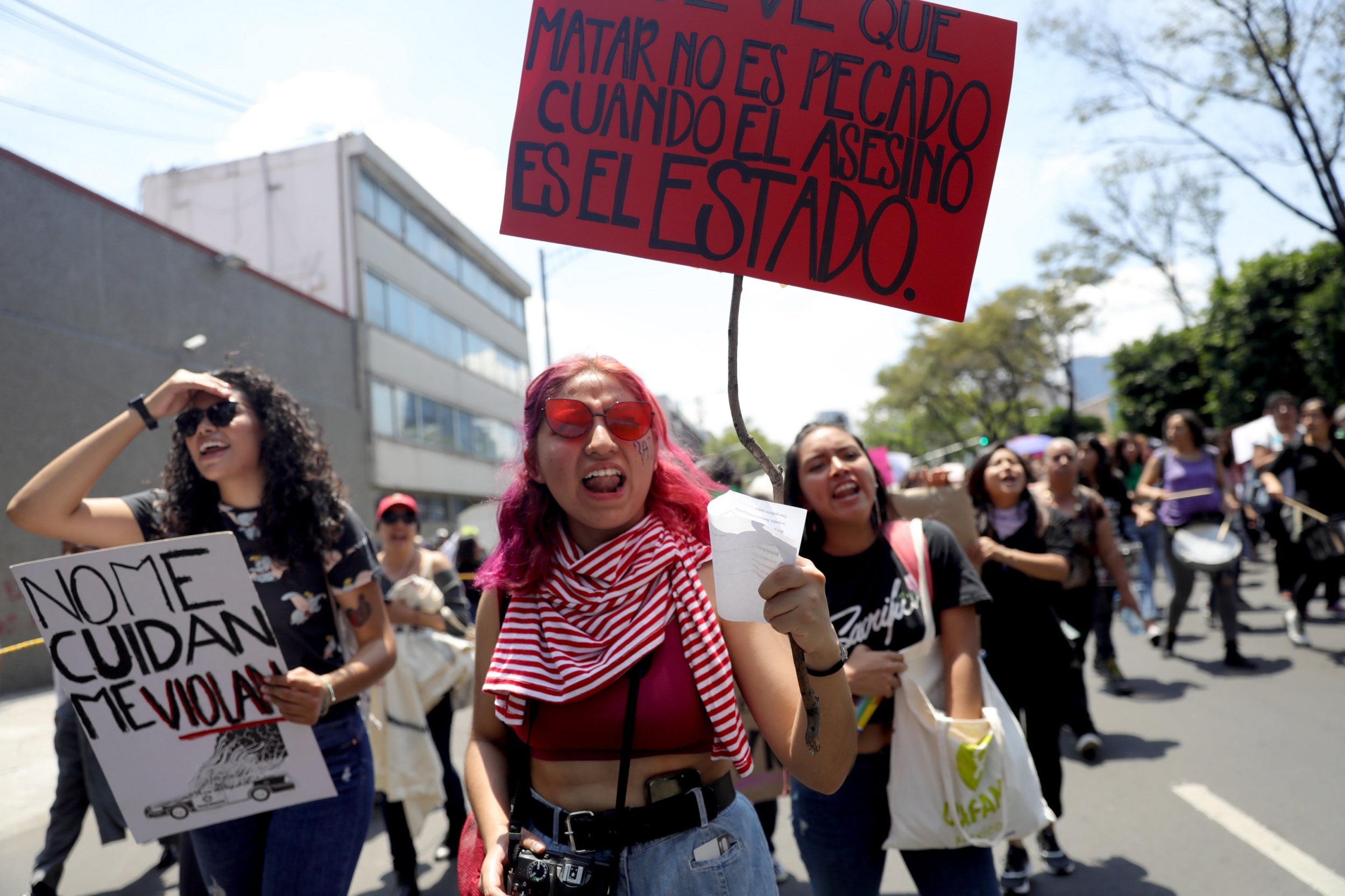 Women hold banners saying 'They don't look after me, they rape me' and 'Killing is not a sin when the murderer is the State' at the protest