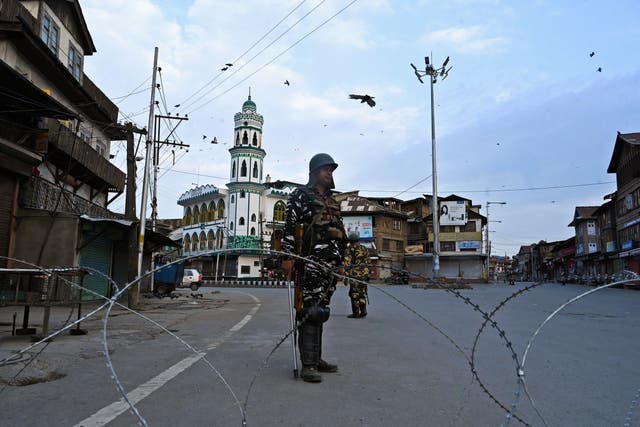 Security personnel stand guard on a street during the lockdown in Srinagar on 12 August