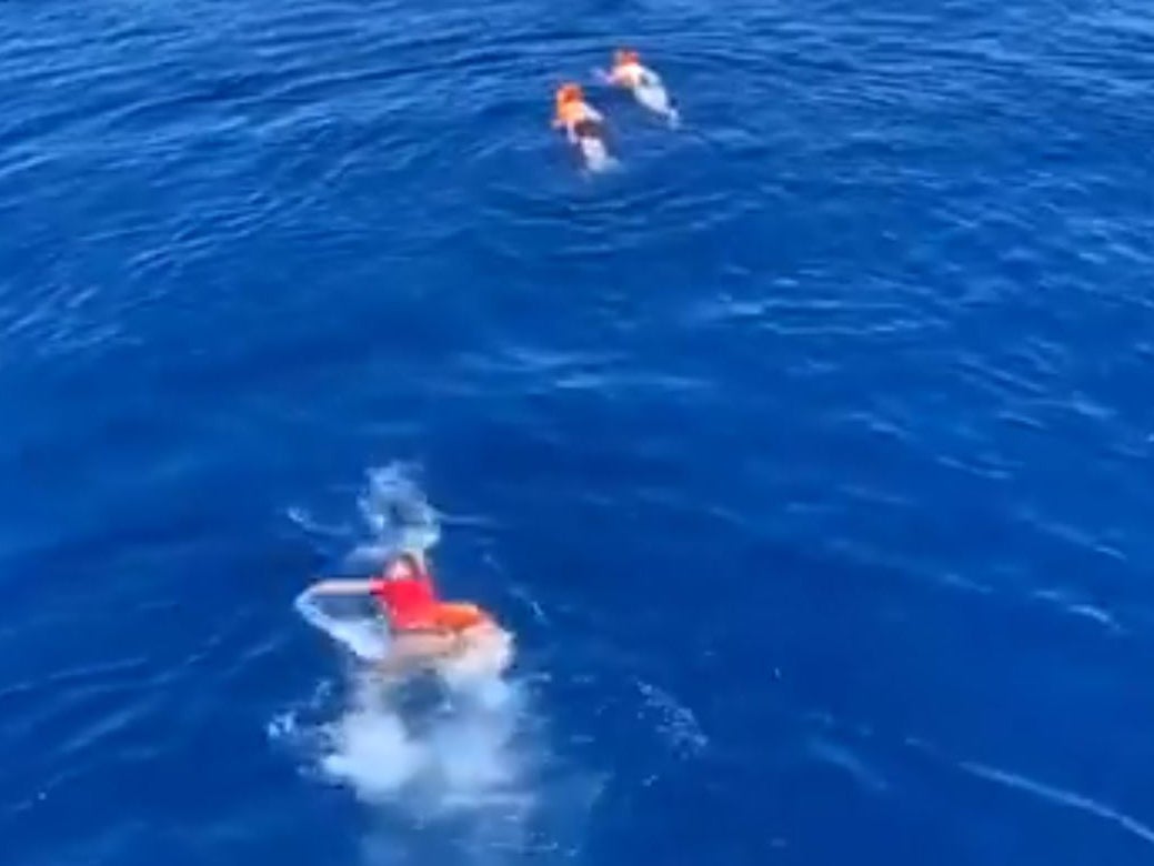 People swim after throwing themselves overboard from the Open Arms rescue ship, having been stuck at sea for days