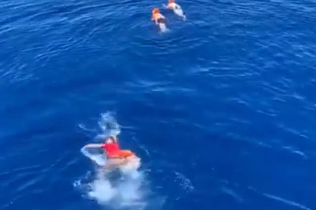 People swim after throwing themselves overboard from the Open Arms rescue ship, having been stuck at sea for days