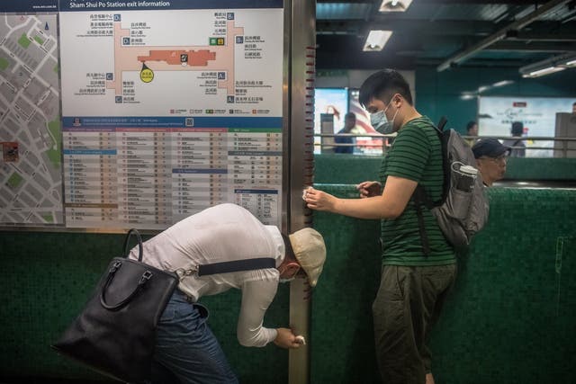 Activists clean an information board at the Sham Shui Po MTR station in Hong Kong on Monday