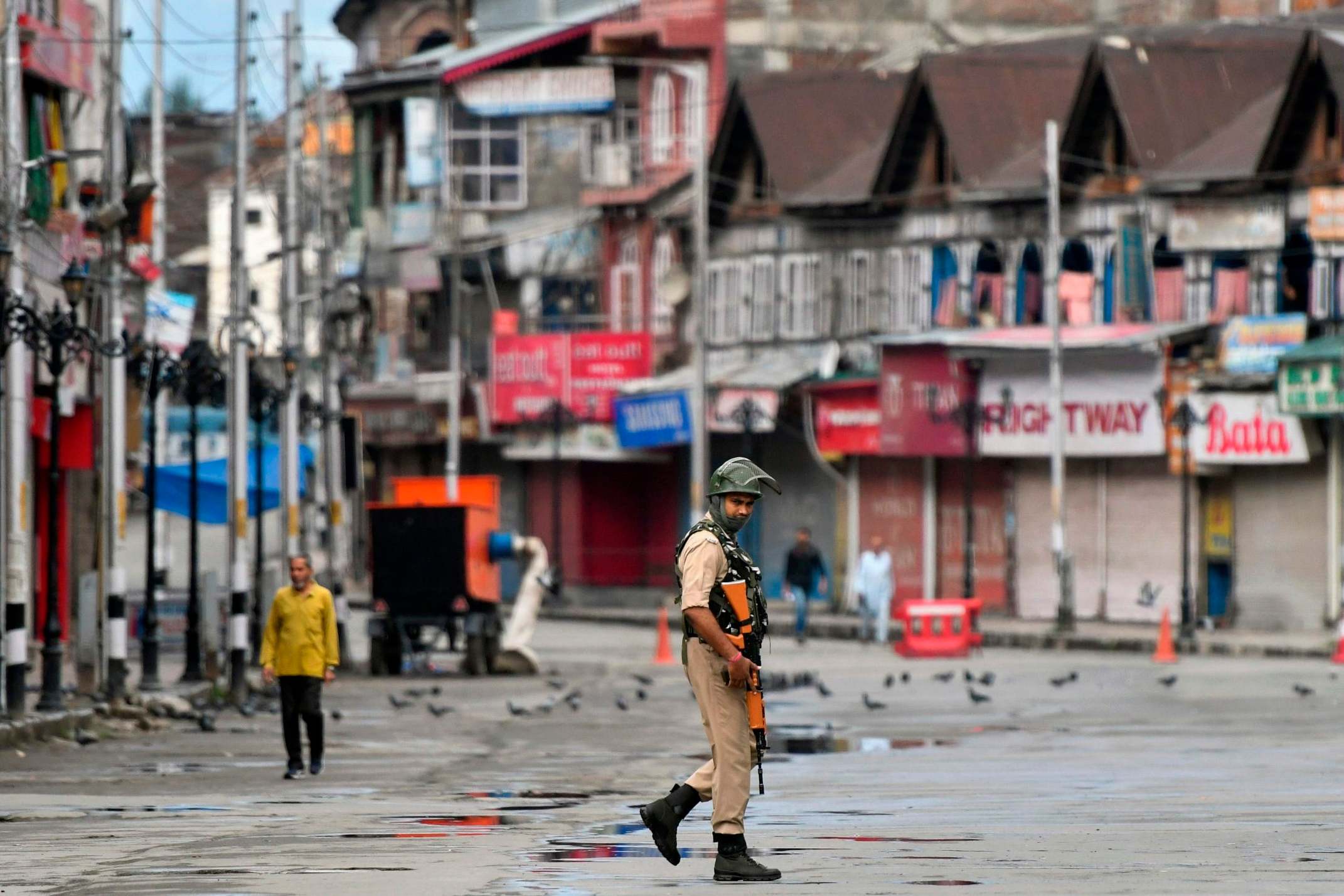 A security forces member patrols a deserted road in Srinagar