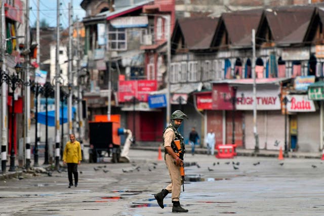 A security personnel patrols on a deserted road of the Lal Chowk area in Srinagar