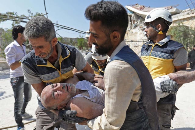 Members of the Syrian Civil Defence (White Helmets) carry an injured man after removing him from under the rubble of a building that collapsed during reported air strikes by pro-regime forces in the village of Beinin, north of Maaret al-Numan, in the northern Idlib province