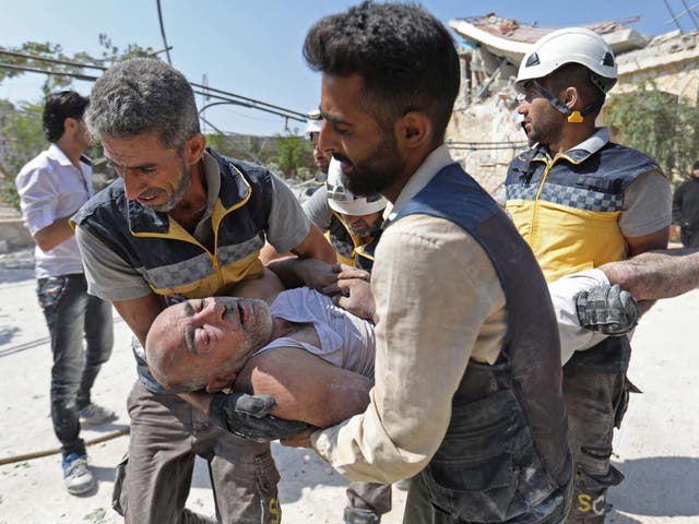 Members of the Syrian Civil Defence (White Helmets) carry an injured man after removing him from under the rubble of a building that collapsed during reported air strikes by pro-regime forces in the village of Beinin, north of Maaret al-Numan, in the northern Idlib province