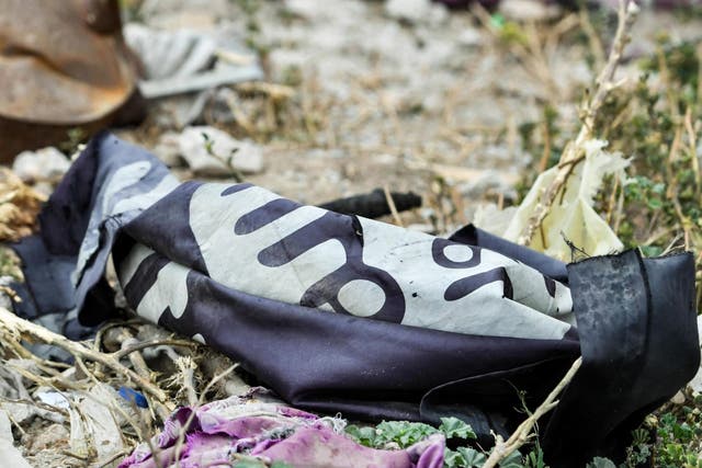 This picture taken in March shows a discarded Islamic State (IS) group flag lying on the ground in the village of Baghouz