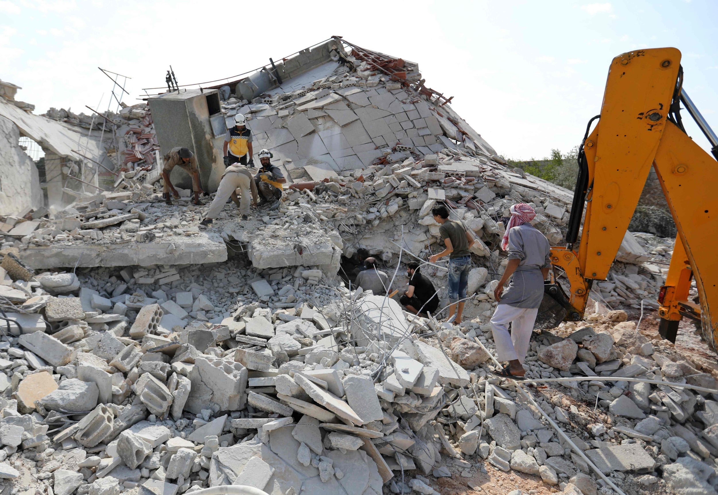 Members of the Syrian Civil Defence (White Helmets) search for victims amidst the rubble of a building that collapsed during reported air strikes by pro-regime forces in the village of Beinin, north of Maaret al-Numan, in the northern Idlib province
