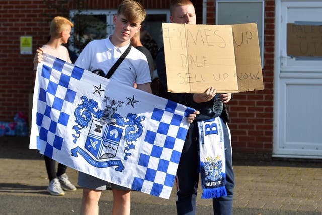 Bury FC fans hold up signage outside the club's Gigg Lane ground as they await news of its future on Friday