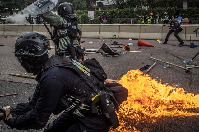 Riot police react after one of the protesters thrown a bottle with flammable liquid during an anti-government march in Kwun Tong, Hong Kong