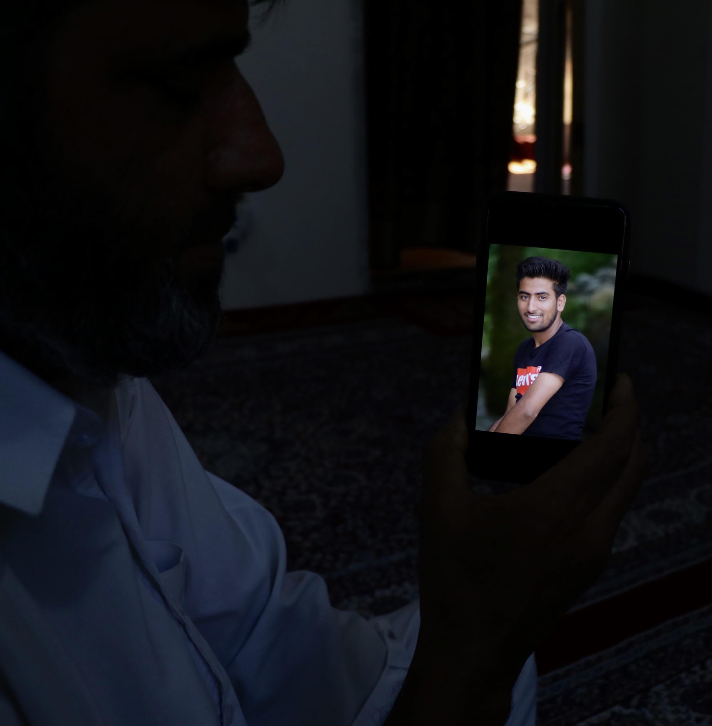 Altaf Ahmad Marazi holds up a picture on a phone of his son Osaib Altaf, 17, who died after jumping in a river to escape security forces in Srinagar