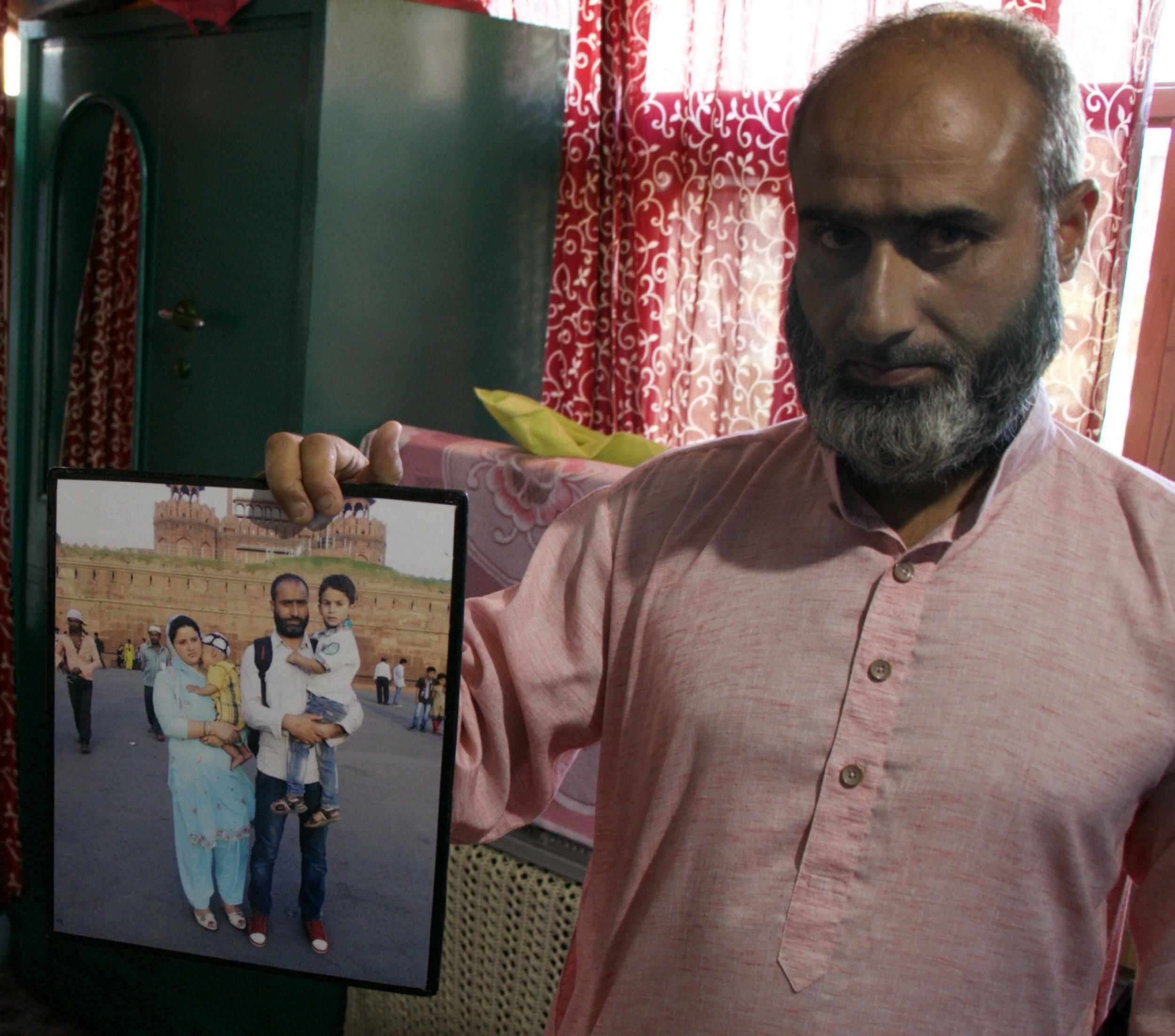 Rafiq Shagoo holds a family photograph of his wife Fehmeeda Bano, 35, and their two sons. Fehmeeda died after inhaling tear gas during clashes