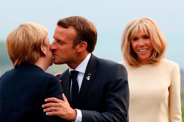 Brigitte Macron looks on as her husband greets German chancellor Angela Merkel at the G7 summit