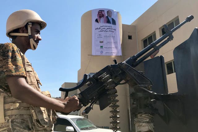A soldier mans a machine gun on a patrol truck in front of a poster of Saudi's King Salman outside a hospital renovated by Saudi Arabia in Aden