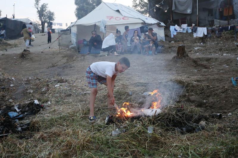 A young refugee lights a fire in a makeshift camp outside Moria on Lesbos (EPA/EFE)