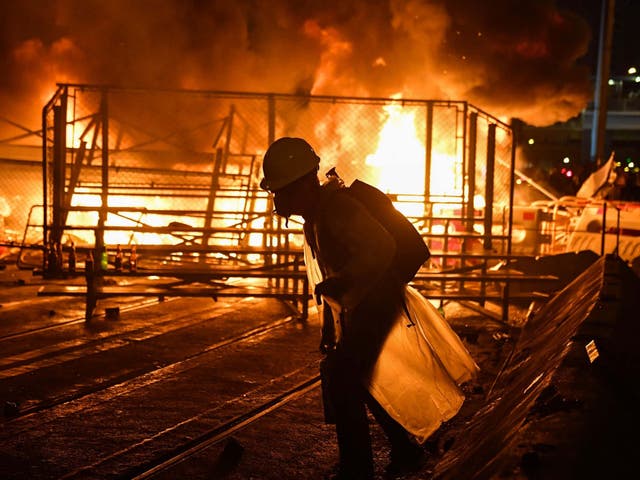 A protester walks before a barricade they set on fire in the Wan Chai district in Hong Kong