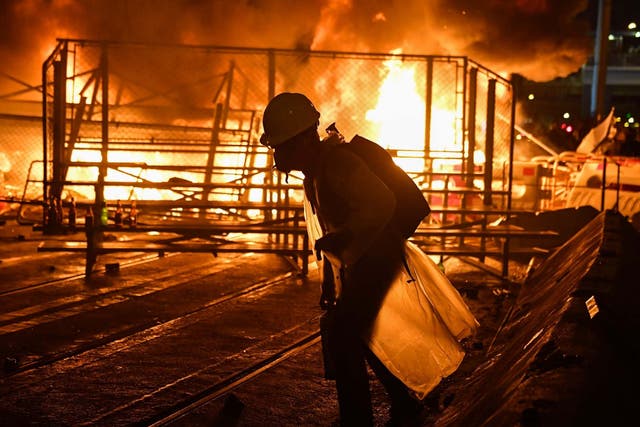 A protester walks before a barricade they set on fire in the Wan Chai district in Hong Kong