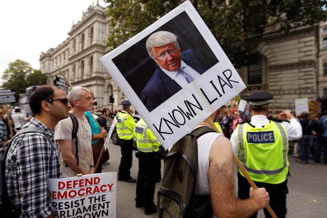 A protester in London yesterday carries a placard with a mock-up of Boris Johnson as Donald Trump