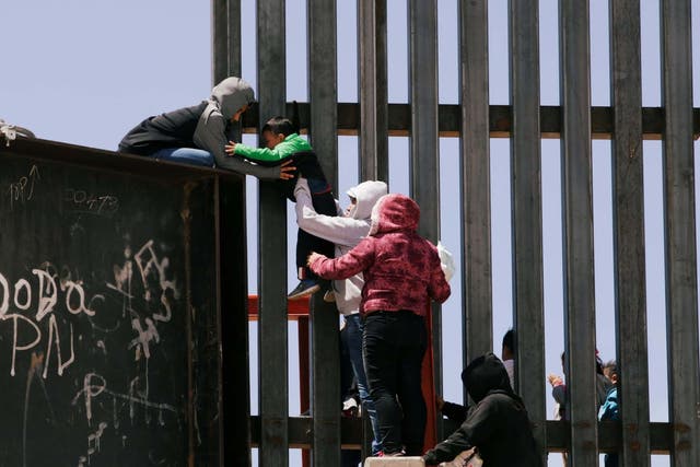 Migrants jump over the border wall to cross the US from Mexico, in Ciudad Juarez.