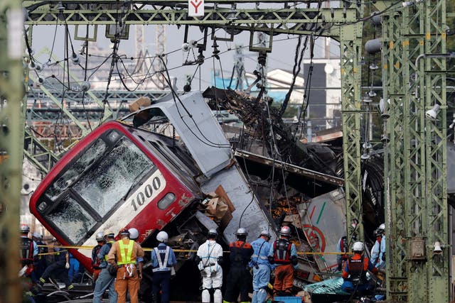 Rescue officers, police and railway company employees work at the scene where a train derailed during a collision with a truck in Yokohama, near Tokyo, Japan