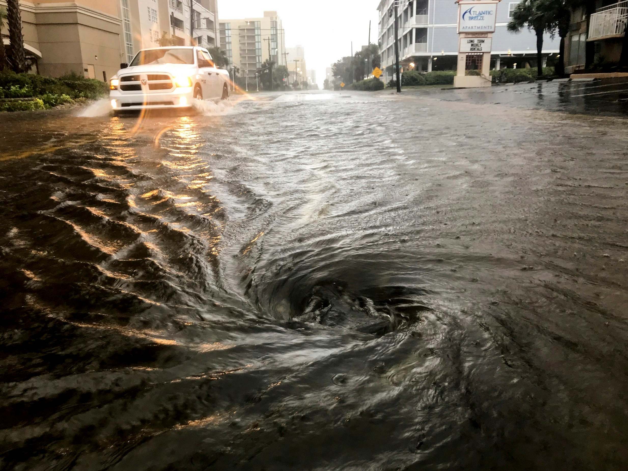 Floodwaters swirl around a storm drain