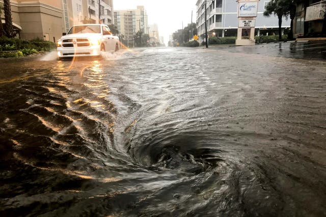 Floodwaters swirl around a storm drain