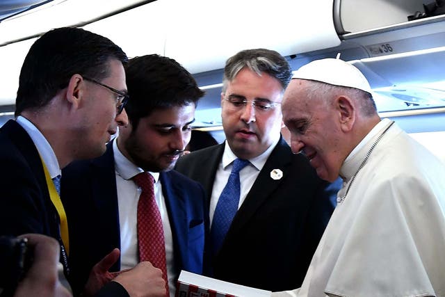 Pope Francis holds the book 'How America Wanted to Change the Pope' on board of the plane on the way to Mozambique