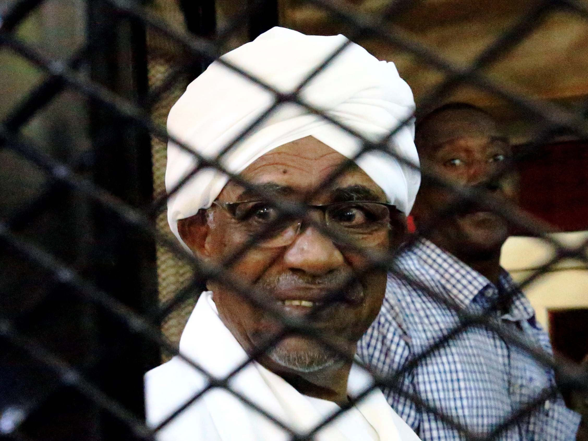 Omar Hassan al-Bashir inside a cage at the courthouse where he is facing corruption charges in late August