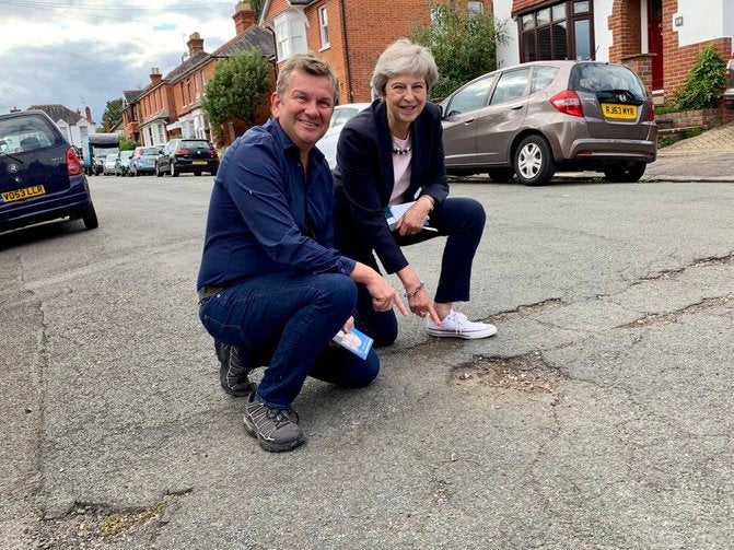 Former prime minister Theresa May poses beside a pothole in her constituency in Maidenhead with local council leader Simon Dudled, 8 September 2019.