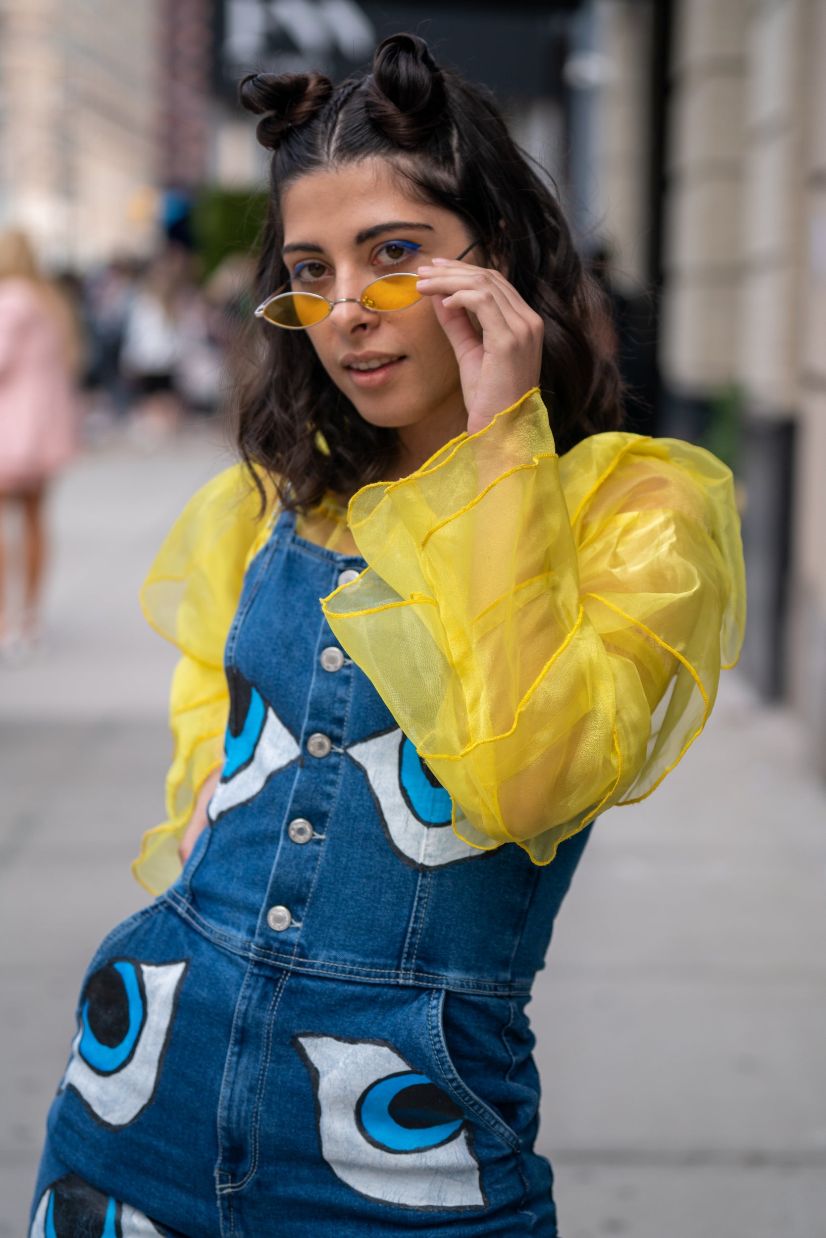 This fashion week attendee encapsulated fashion's playful spirit in this look, consisting of full-length dungarees covered with eye motifs, which she wore over a sheer egg yolk yellow shirt.