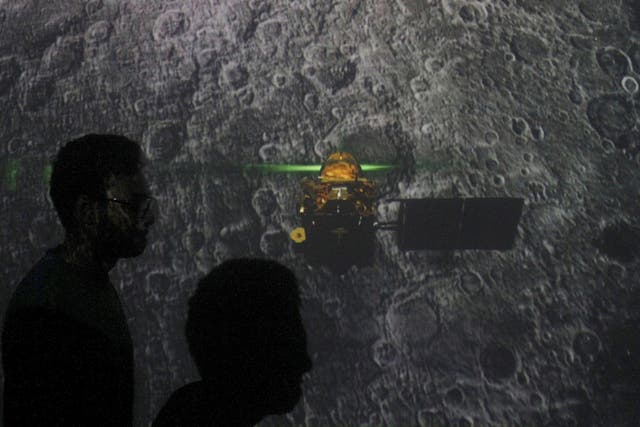 Student walk past a screen during a live streaming of Chandrayaan-2 landing at an educational institute in Mumbai, India