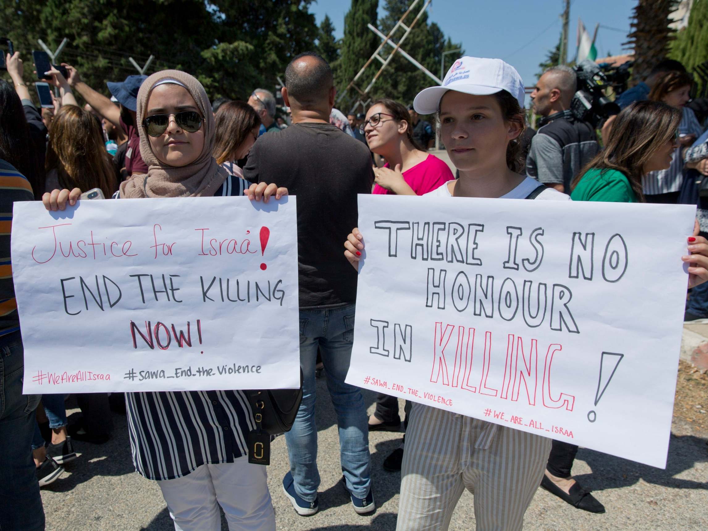 Two Palestinian women hold placards during a rally over the death of Israa Ghrayeb, suspected to have died by honour killing