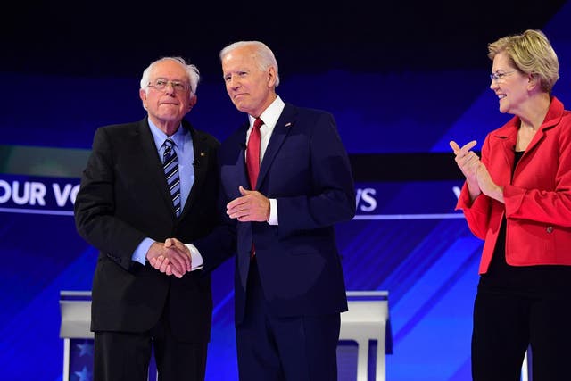 Democratic presidential hopeful Elizabeth Warren (R) looks on as Joe Biden and Bernie Sanders shake hands ahead of third Democratic debate
